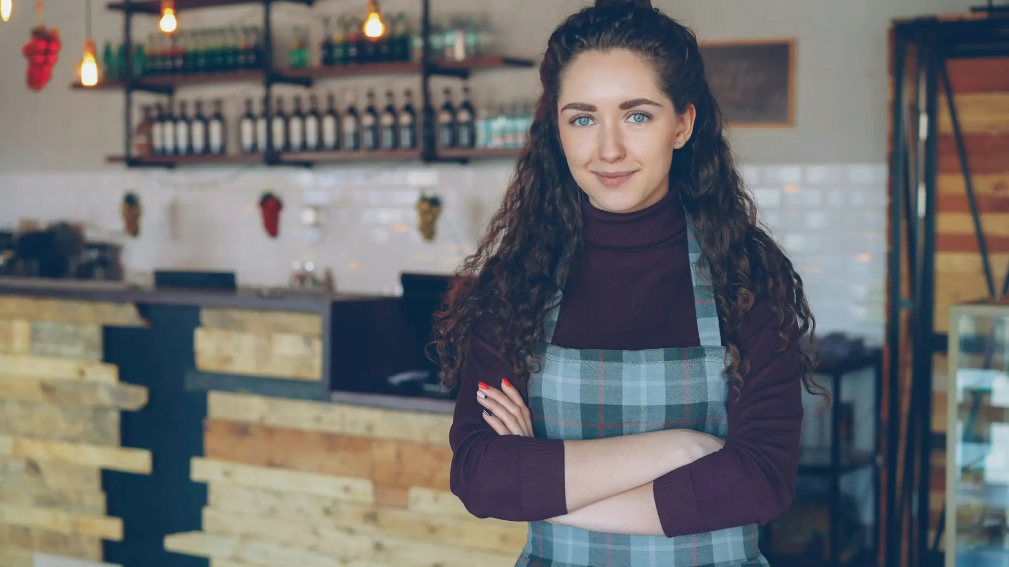 Smiling café owner standing behind the counter of her coffee shop