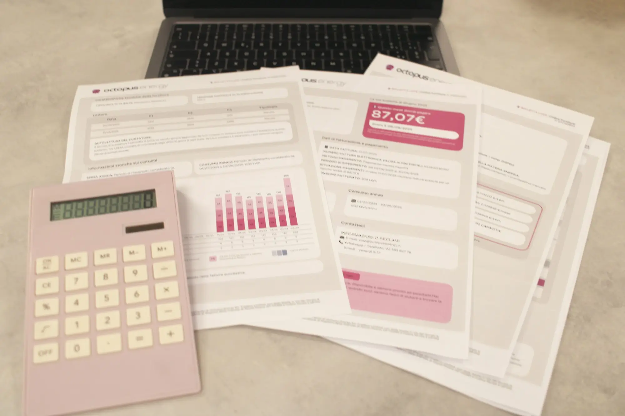 Bills, a calculator and a laptop spread across a desk while the month's finances are worked through